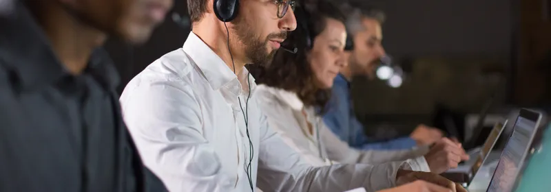 Técnicos con auriculares atendiendo una mesa de ayuda frente a sus computadoras